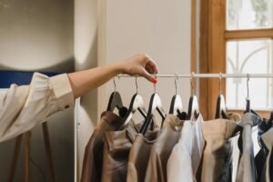 A woman's hand with red nails selecting leather jackets on hangers. Fashion store