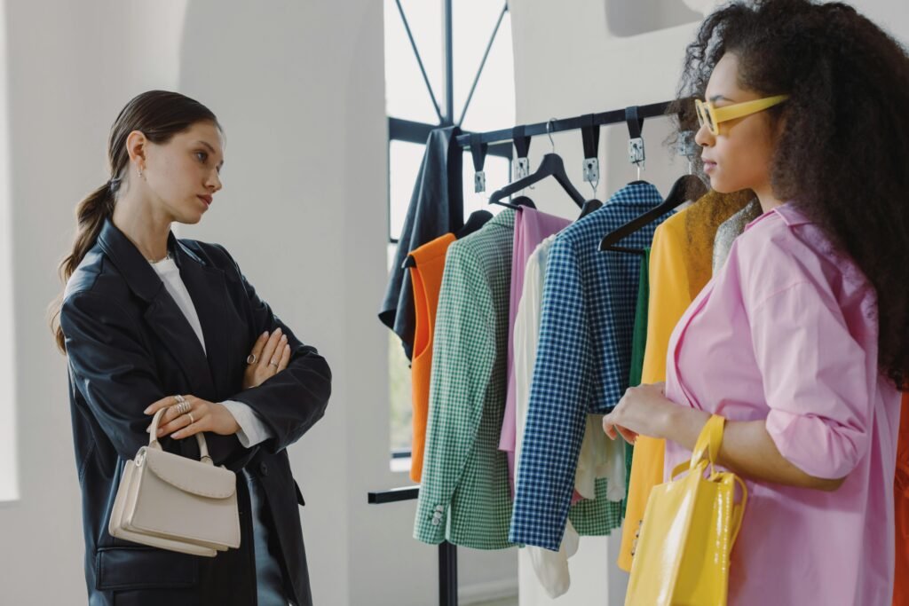 Two women browsing colorful clothing racks in a modern boutique. Fashion store